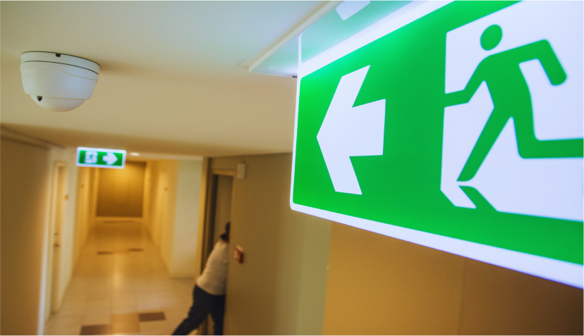 ödutrymningsskylt i korridor som visar säkra utrymningsvägar och regelbunden service av nödbelysning och evakueringssystem